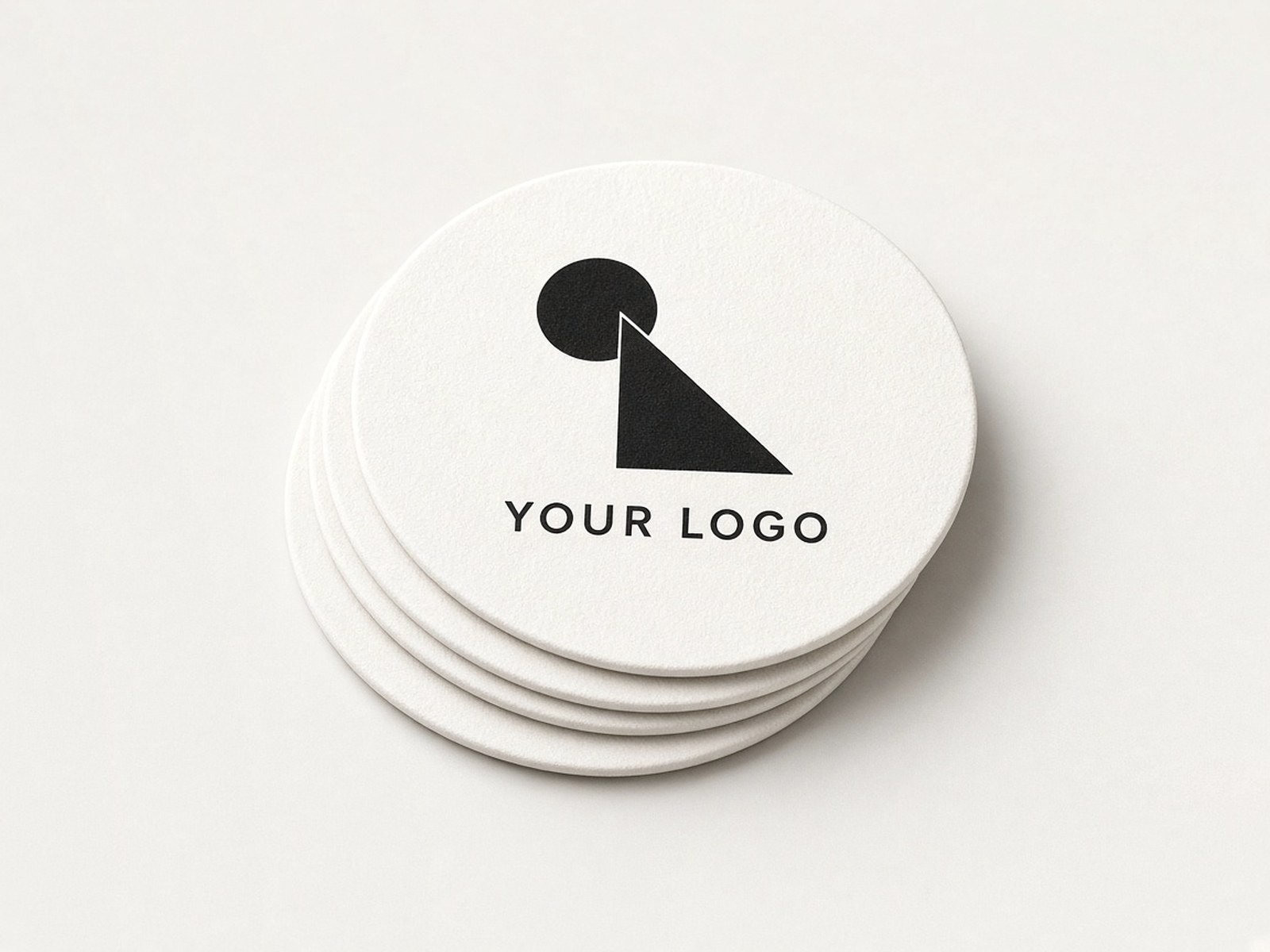 A small stack of round white paper coasters printed in black with an example logo.